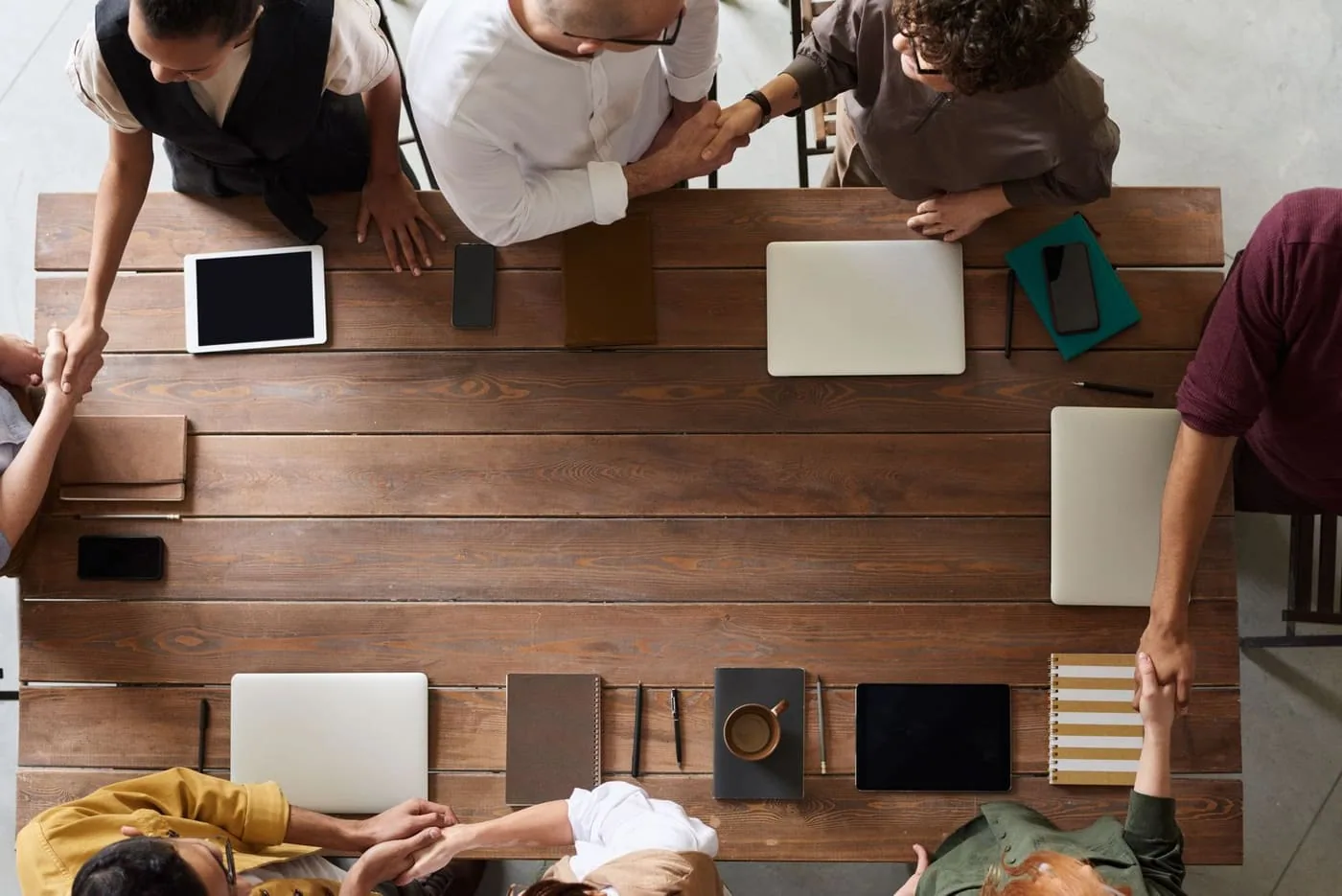 Two teams shaking hands across a meeting table
